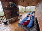 Main floor porch with a wood burning fireplace with a flat screen tv and a gas girll  